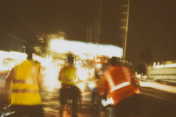 Blurred urban lights and ciclists silhouettes — Stock Photo, Image