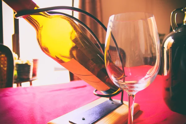 红色桌子上的一瓶葡萄酒和玻璃 — 图库照片