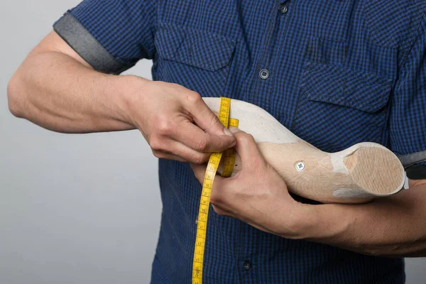Close up of hands of an orthopedic shoemaker measuring a wooden last for quality control
