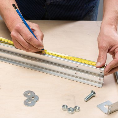 Tahta bir tezgahta alüminyum bir profil üzerinde çalışmak ve ölçmek