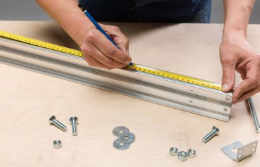 Tahta bir tezgahta alüminyum bir profil üzerinde çalışmak ve ölçmek