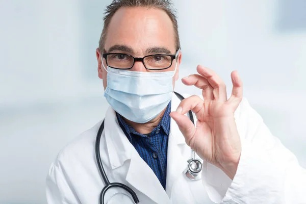 male doctor with face mask makes a everything okay gesture