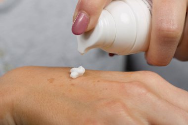 Kadın eline sürdüğün cilt losyonunu kapat.