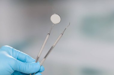 Diş aletlerini gösteren mavi eldivenli dişçinin elini kapat.