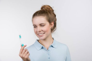 Genç kız diş fırçasına bakıyor.