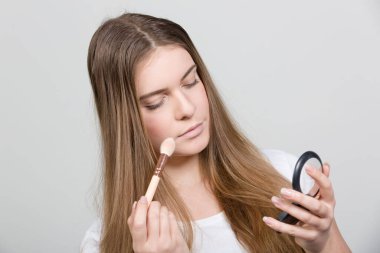 Genç kadın her gün makyaj pudrası sürüyor. 