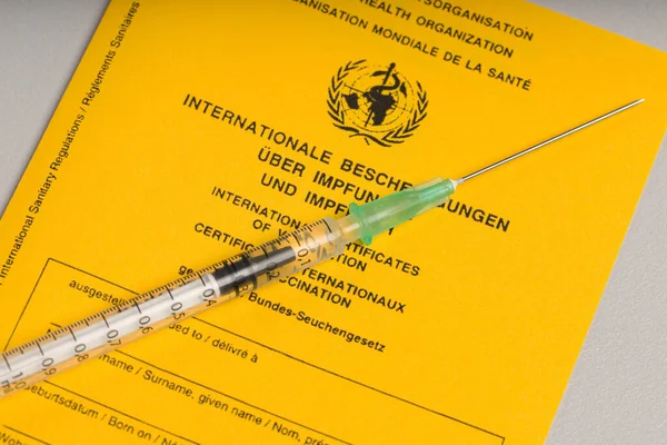 international certificate of vaccination and a syringe with covid-19 vaccine