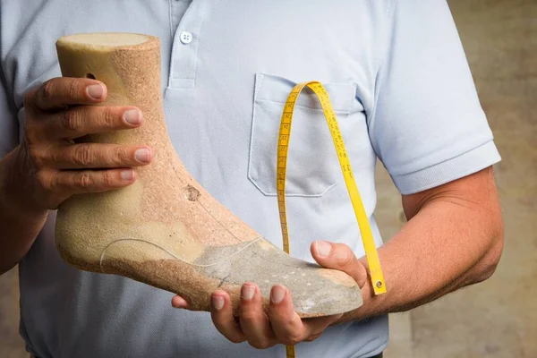 Close up of hands of an orthopedic shoemaker controlling and presenting an individual crafted wooden last