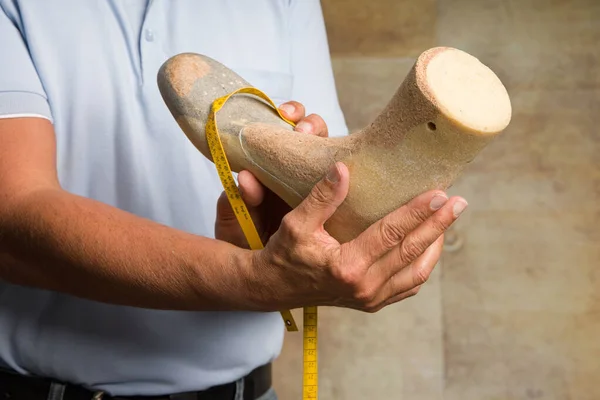 Close up of hands of an orthopedic shoemaker controlling and presenting an individual crafted wooden last