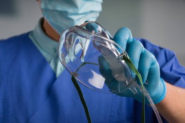 close-up of icu doctor's hand with disposable oxygen mask for breathing support 