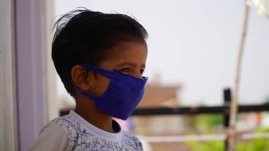 Hafif arka planda tek kullanımlık maskeli küçük bir kız. Çin virüs salgını koruması