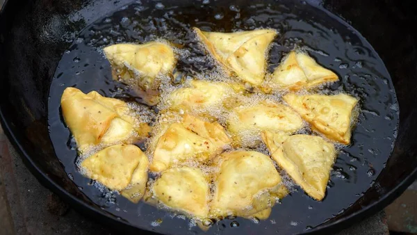 萨莫萨在一个巨大的黑色卡戴或与大量的石油煎锅中被深深的烧焦 印度著名的街头美食在黑色的卡迪海上油炸 — 图库照片