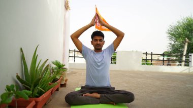 Serene Hintli adam dışarıda yoga yapıyor. Genç yoga uygulayıcısı nilüfer çiçeğinin içinde gözleri kapalı oturuyor. Yoga ve meditasyon konsepti