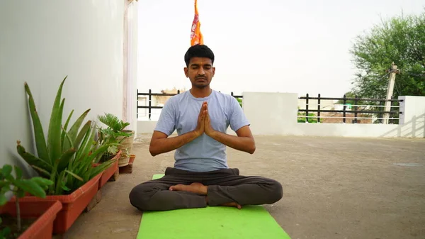 Serene Hintli adam dışarıda yoga yapıyor. Genç yoga uygulayıcısı nilüfer çiçeğinin içinde gözleri kapalı oturuyor. Yoga ve meditasyon konsepti