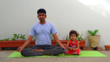 Yerde oturmuş meditasyon yapan sakin bir adamın portresi. Yazın gökyüzü arka planında yoga egzersizleri yapan beyaz bir genç. Savaşçı pozu