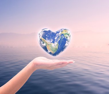 World in heart shape with over women human hands