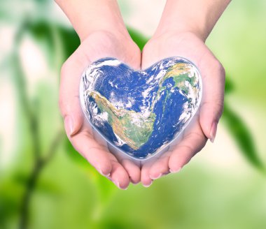 World in heart shape with over women human hands