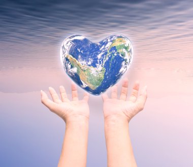 World in heart shape with over women human hands