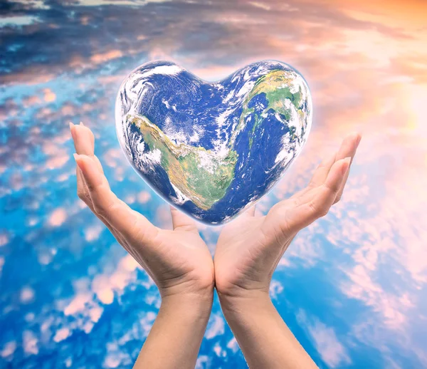 World in heart shape with over women human hands