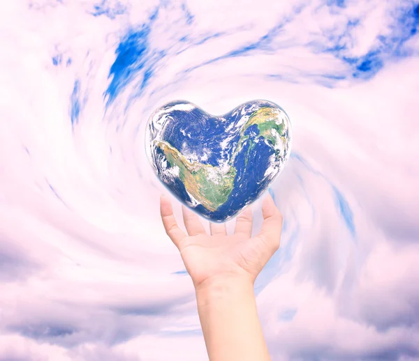 World in heart shape with over women human hands — Stockfoto