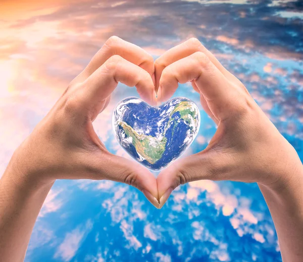World in heart shape with over women human hands