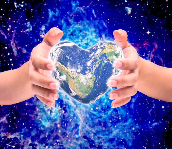 Wereld in hart vorm met over de menselijke handen vrouwen op wazig natu — Stockfoto