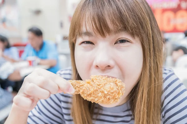 Mladá šťastná žena držící a jíst hranolky kuřecí — Stock fotografie