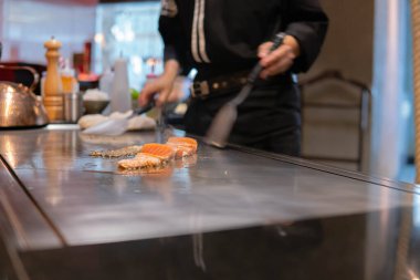 Şefin eli somon bifteği pişiriyor.