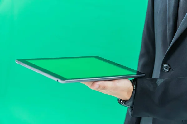 hands holding tablet computer on light green background