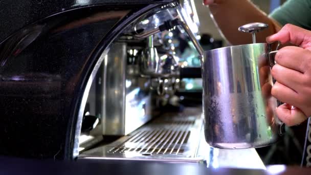 Színes felvétel egy baristáról, amint forró vizet önt egy fémes bögrébe.. — Stock videók
