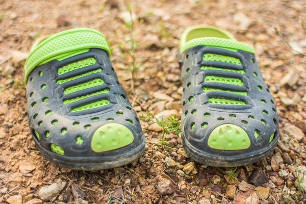 Ζευγάρι παντόφλες πράσινο βρώμικο στο χώμα. — Φωτογραφία Αρχείου