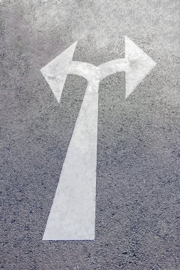 Siyah asfalt yol yüzeyinde iki yönlü bir ok sembolü.