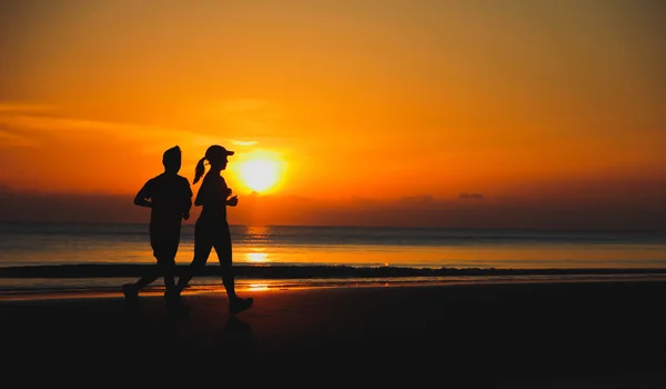 Молодая пара: мужчина и женщина бегают вместе на закате на озере Коа — стоковое фото