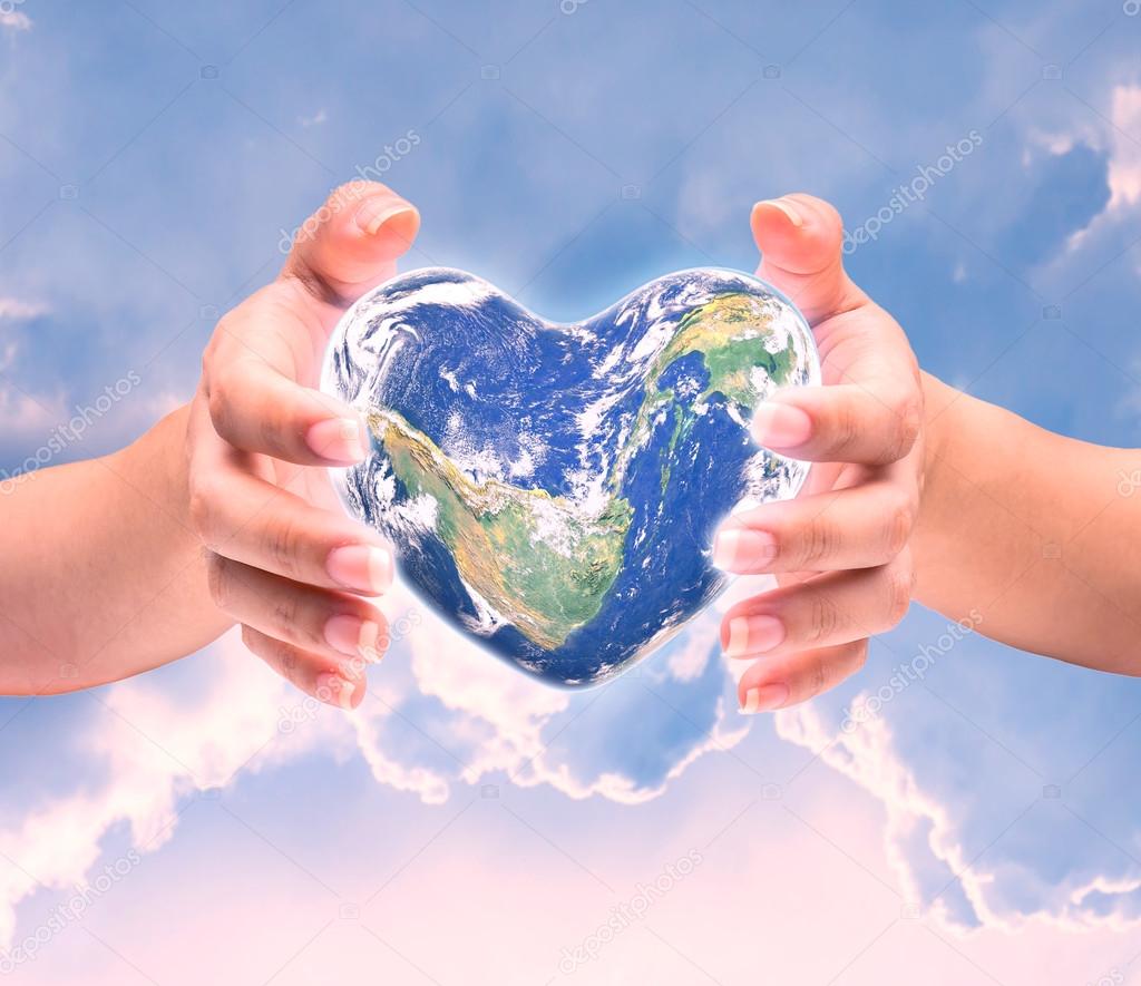 World in heart shape with over women human hands on blurred natu