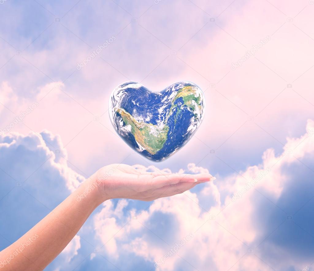 World in heart shape with over women human hands on blurred natu