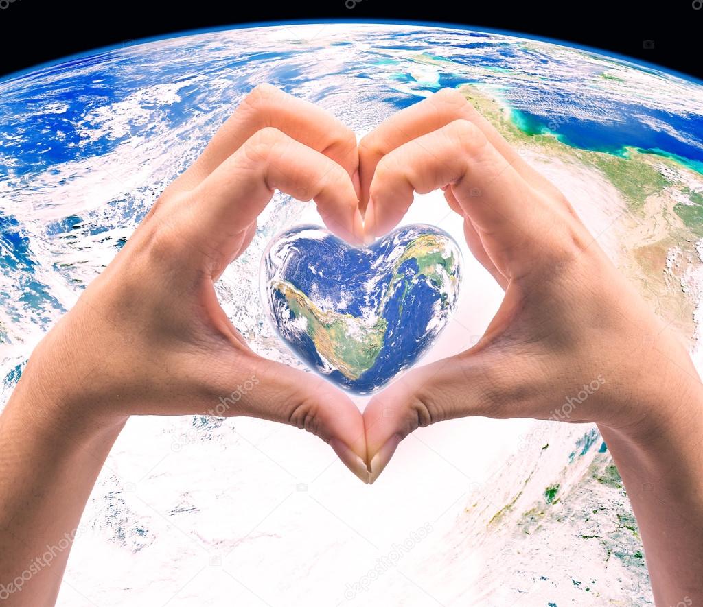 World in heart shape with over women human hands on blurred natu