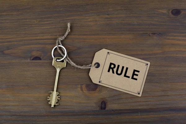 Κλειδί και ένα σημείωμα σχετικά με ένα ξύλινο τραπέζι με κείμενο - κανόνα — Φωτογραφία Αρχείου