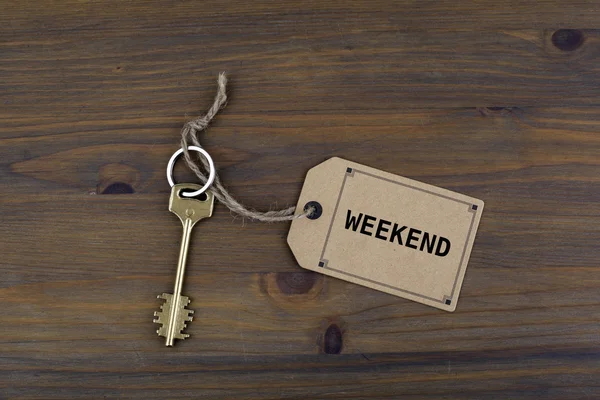 Κλειδί και ένα σημείωμα σχετικά με ένα ξύλινο τραπέζι με κείμενο - το Σαββατοκύριακο — Φωτογραφία Αρχείου