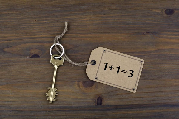 Clave y una nota sobre una mesa de madera con texto. Concepto de sinergia — Foto de Stock