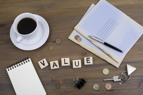 Caffè, penna, denaro e blocco su una scrivania e parola Valore — Foto Stock