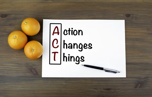 Wooden background with oranges and text: Action Changes Things ( — Stock fotografie