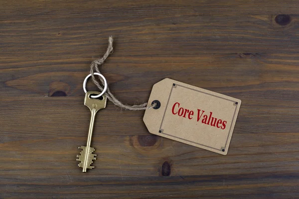 Ключ и записка на деревянном столе с текстом - основные ценности — стоковое фото