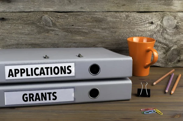 Applications and Grants - two folders on wooden office desk — Stock Photo, Image