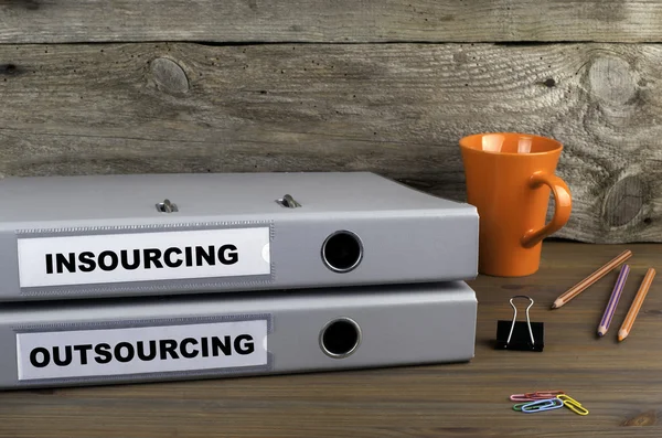 Insourcing ve dış kaynak - ahşap ofis masasında iki klasör — Stok fotoğraf