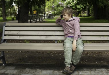 Parkta cep telefonu konuşurken çocuk