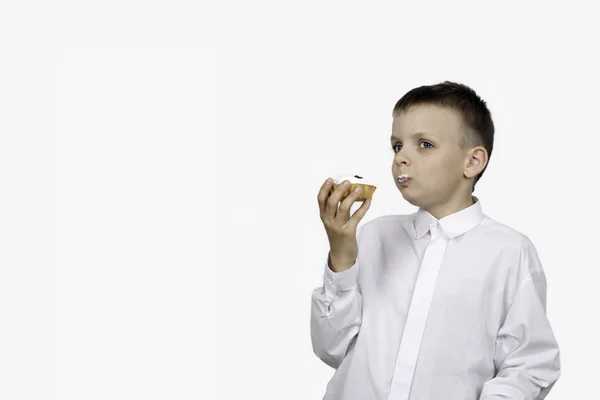 Niño con un pastel de crema en las manos sobre un fondo blanco — Foto de Stock