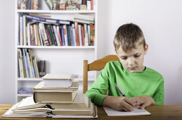 Student jongen met boek schrijven naar notebook thuis — Stockfoto
