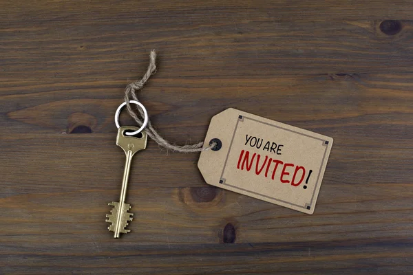 Key and a note on a wooden table with text - You Are Invited! — Stock Photo, Image