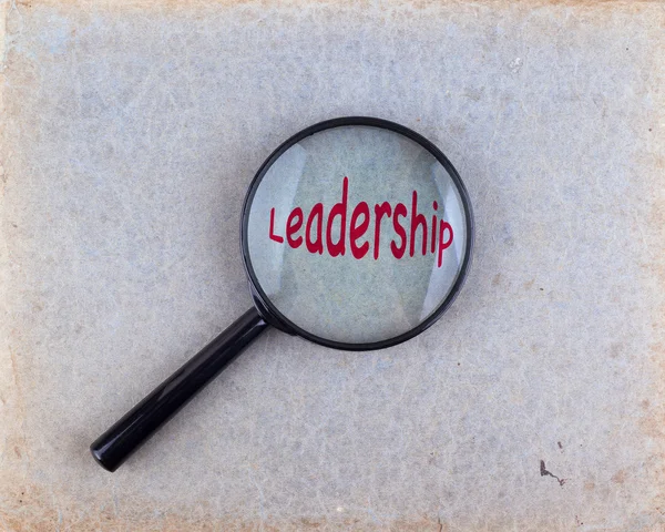 Leadership. Lente d'ingrandimento ottica su vecchio sfondo di carta — Foto Stock