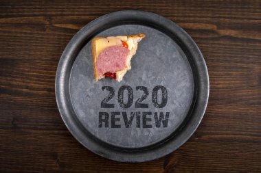 2020 gözden geçirme konsepti. Metal bir tabakta ısırılmış sandviç. Koyu renk ahşap.